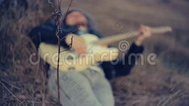 日落时分，一个男人躺在橡树下弹吉他